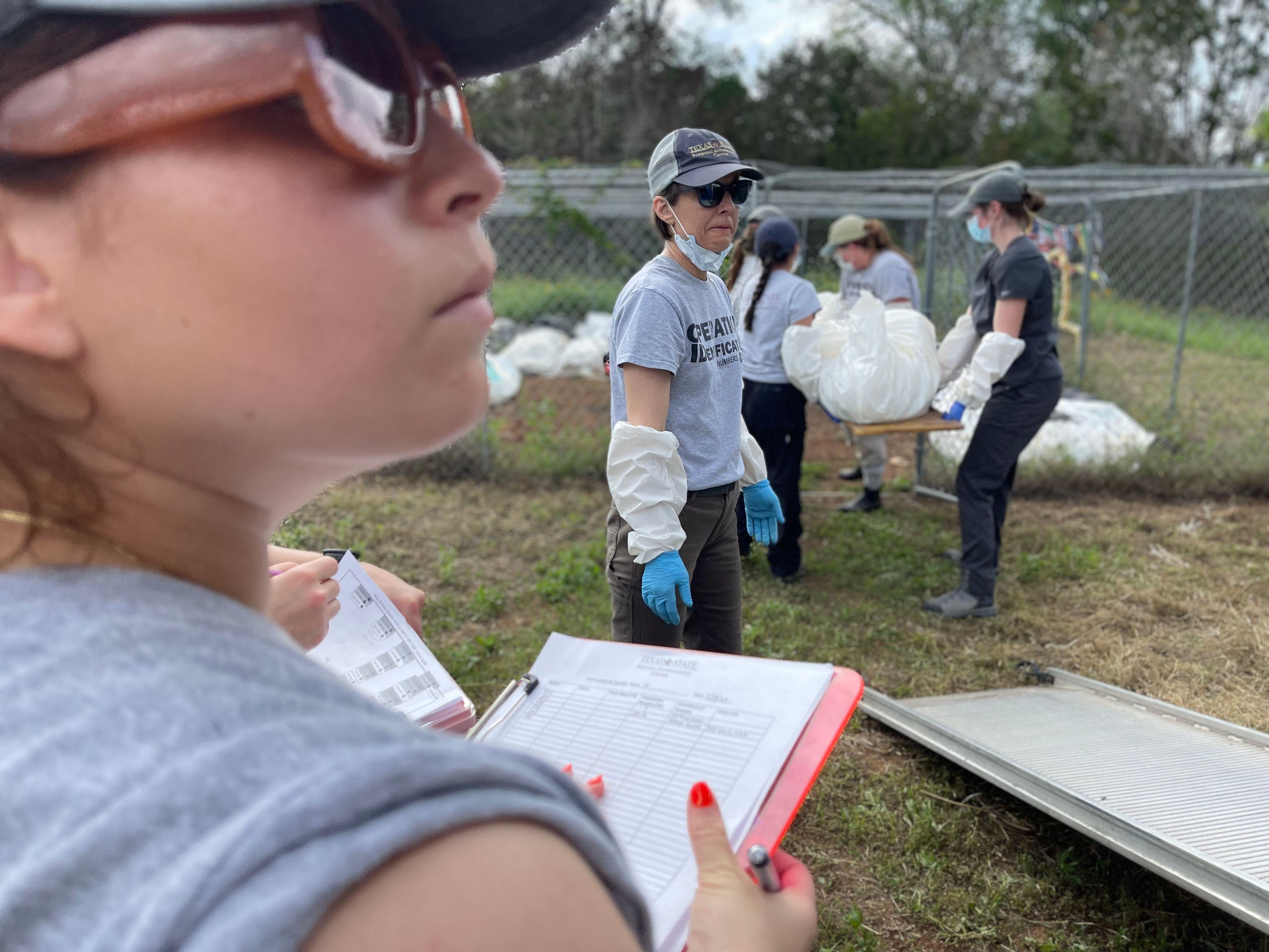 Kate Spradley (en el centro) e Ivanna Robledo (en primer plano), en Freeman Ranch descargando cadáveres de migrantes procedentes del condado de Maverick, en Texas.
