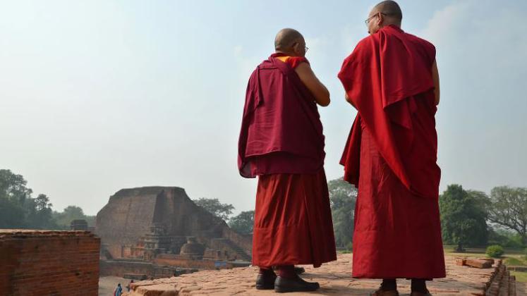 Dois homens com trajes budistas de frente para paisagem
