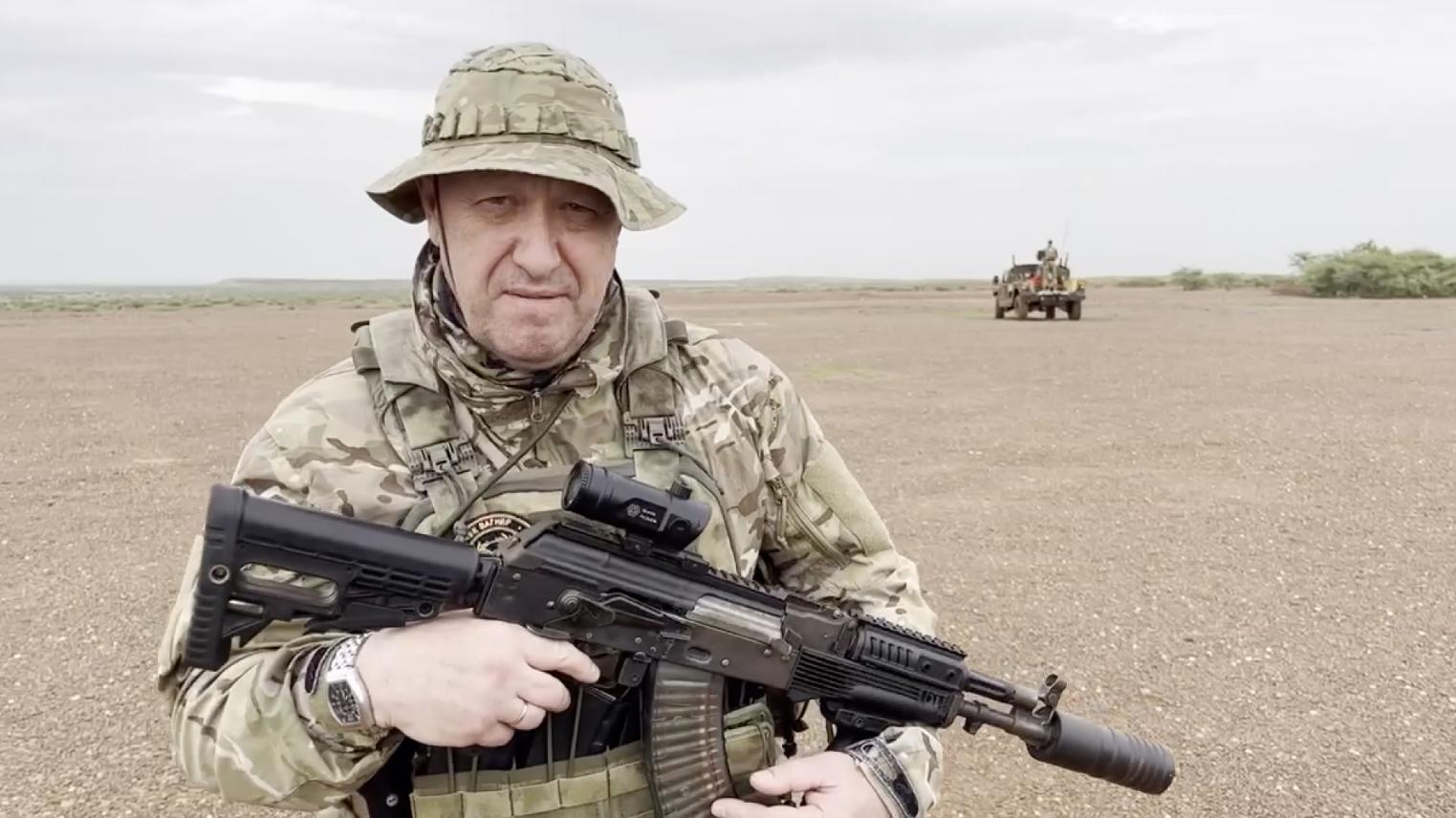 Yevgeny Prigozhin vestido con uniforme militar sosteniendo un rifle.