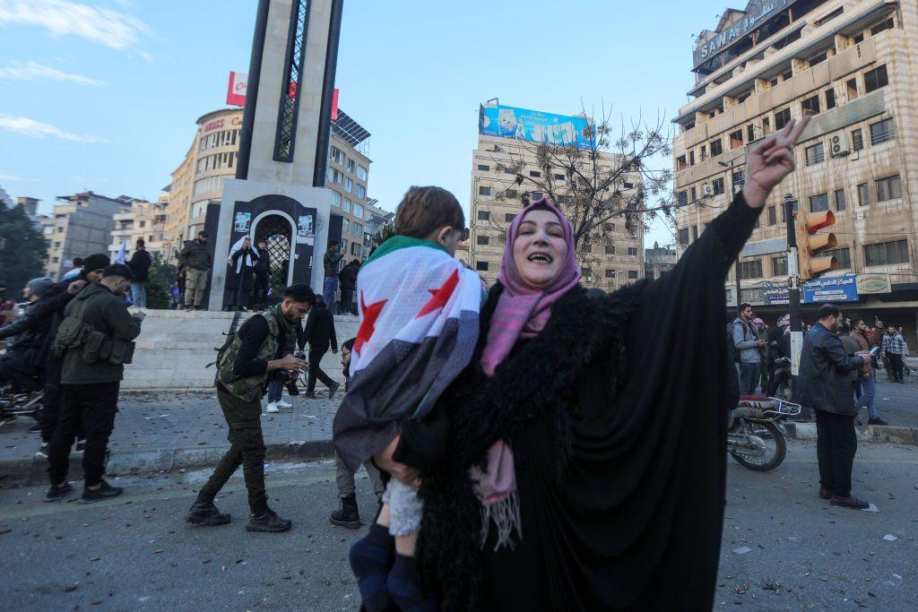 Una mujer con un niño en brazos celebra en la plaza Omeya la entrada de las fuerzas rebeldes sirias en Damasco, el 8 de diciembre de 2024.