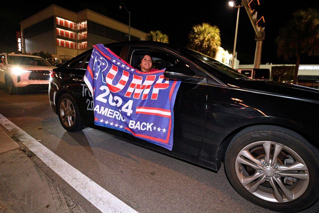 Mujer en un coche con pancarta de Trump