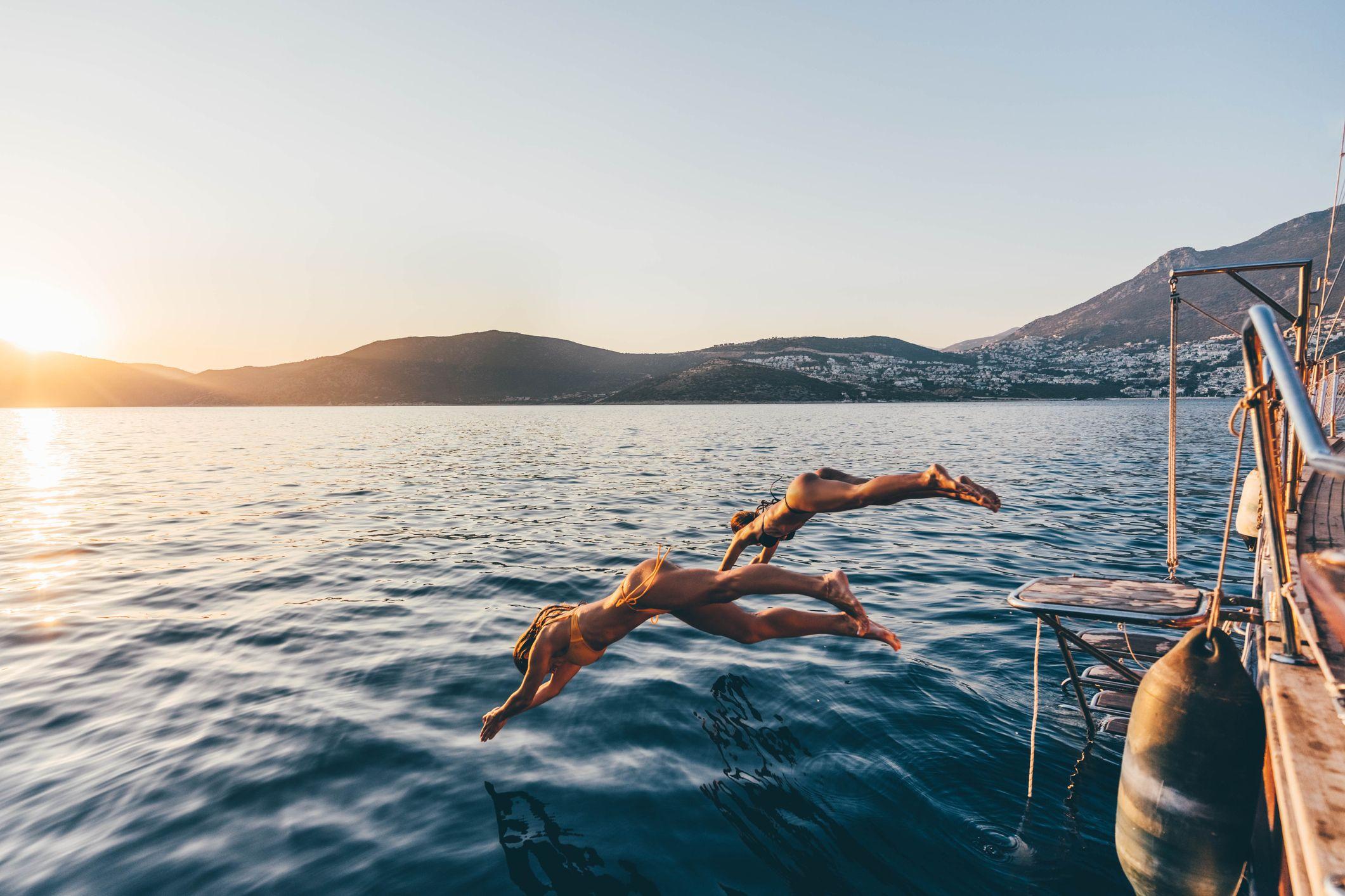 Duas mulheres saltando de barco no mar