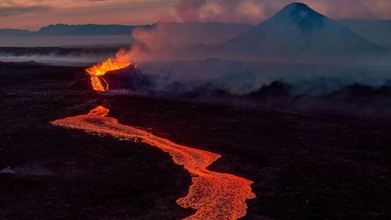 A língua de lava emitida da cratera flui lentamente morro abaixo