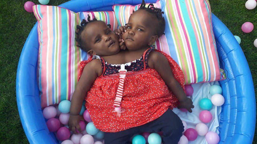 Marieme e Ndeye quando eram bebês, com roupas de calor, deitadas em uma piscina de bolinhas