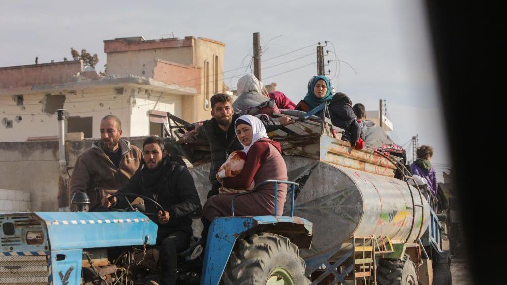 صورة تظهر أشخاصاً نازحين من مناطق القتال في سوريا وهم يستقلون مركبة زراعية.