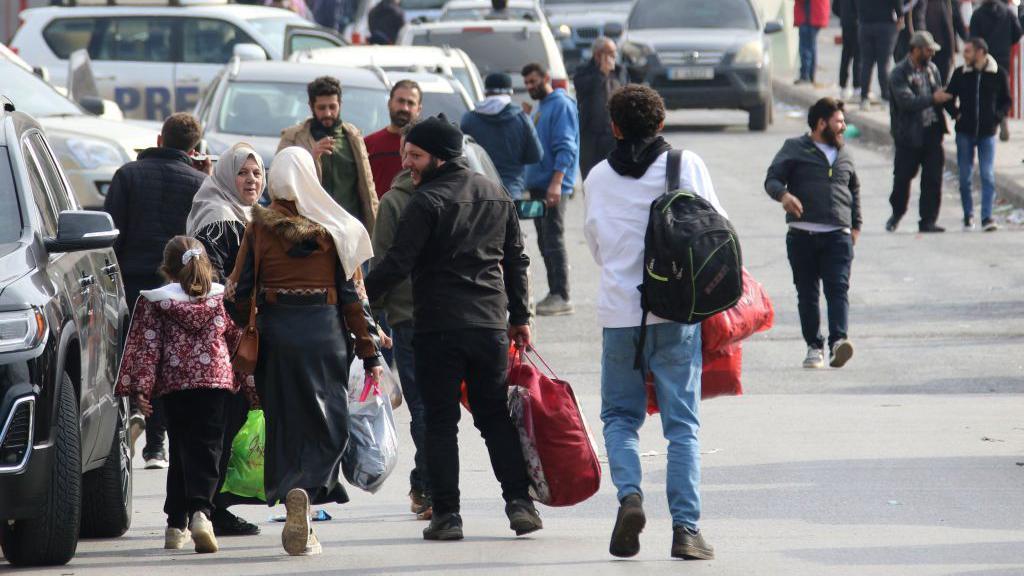 Refugiados sírios caminhando em direção ao posto de fronteira de Masnaa, entre o Líbano e a Síria, para voltar para casa em 8 de dezembro de 2024, após a queda do regime de Bashar al-Assad