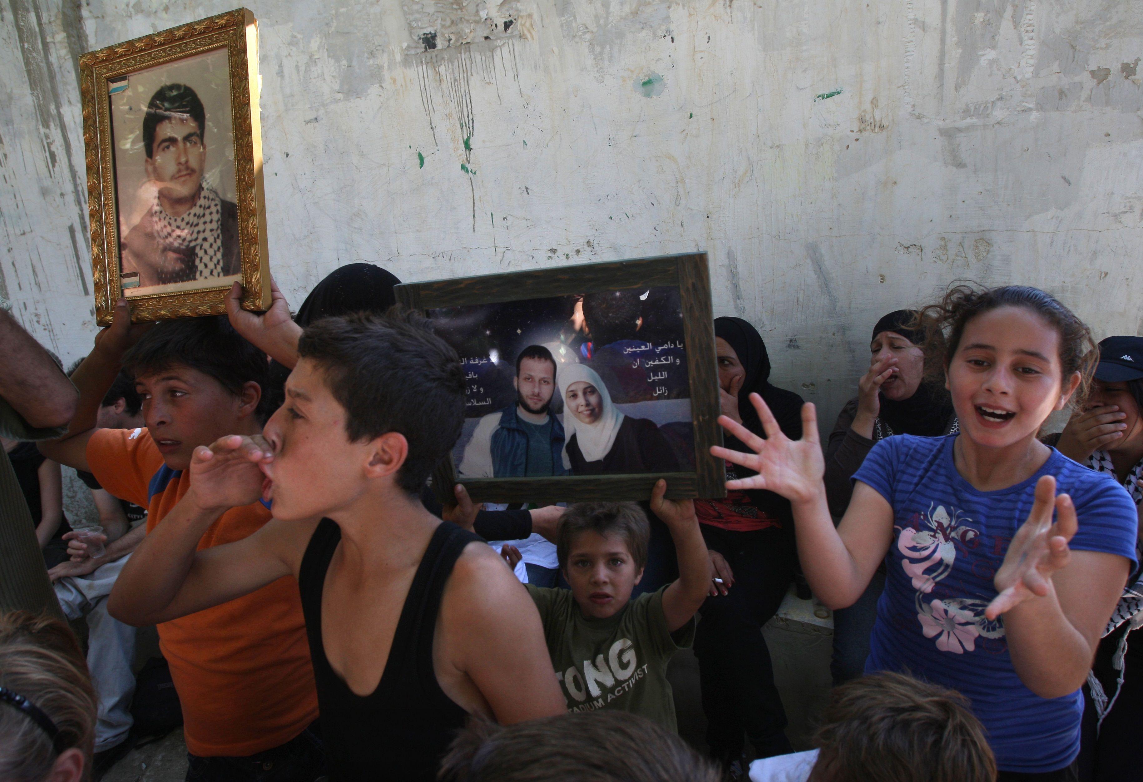 فلسطينيون من قرية النبي صالح في الضفة الغربية يحتفلون بالإفراج المرتقب عن أحلام التميمي ونزار التميمي الظاهرين في الصورة اليمنى، في 14 أكتوبر/تشرين الأول 2011