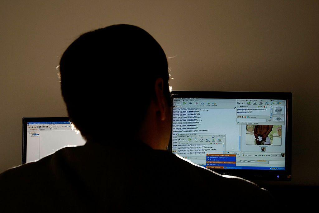 Un hombre viendo unas pantallas de computador de espalda