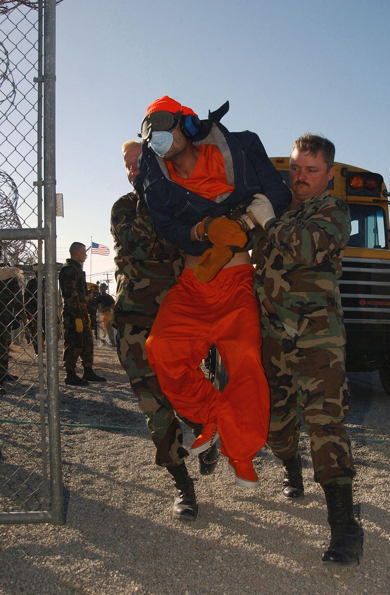 Dos soldados llevan en volandas a un prisionero.