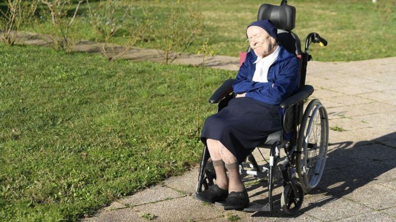 Lucile Randon em cadeira de rodas pegando sol ao ar livre