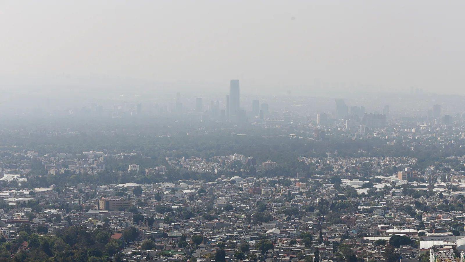 Imagem aberta de uma grande cidade vista do alto com o céu acinzentado por poluição.