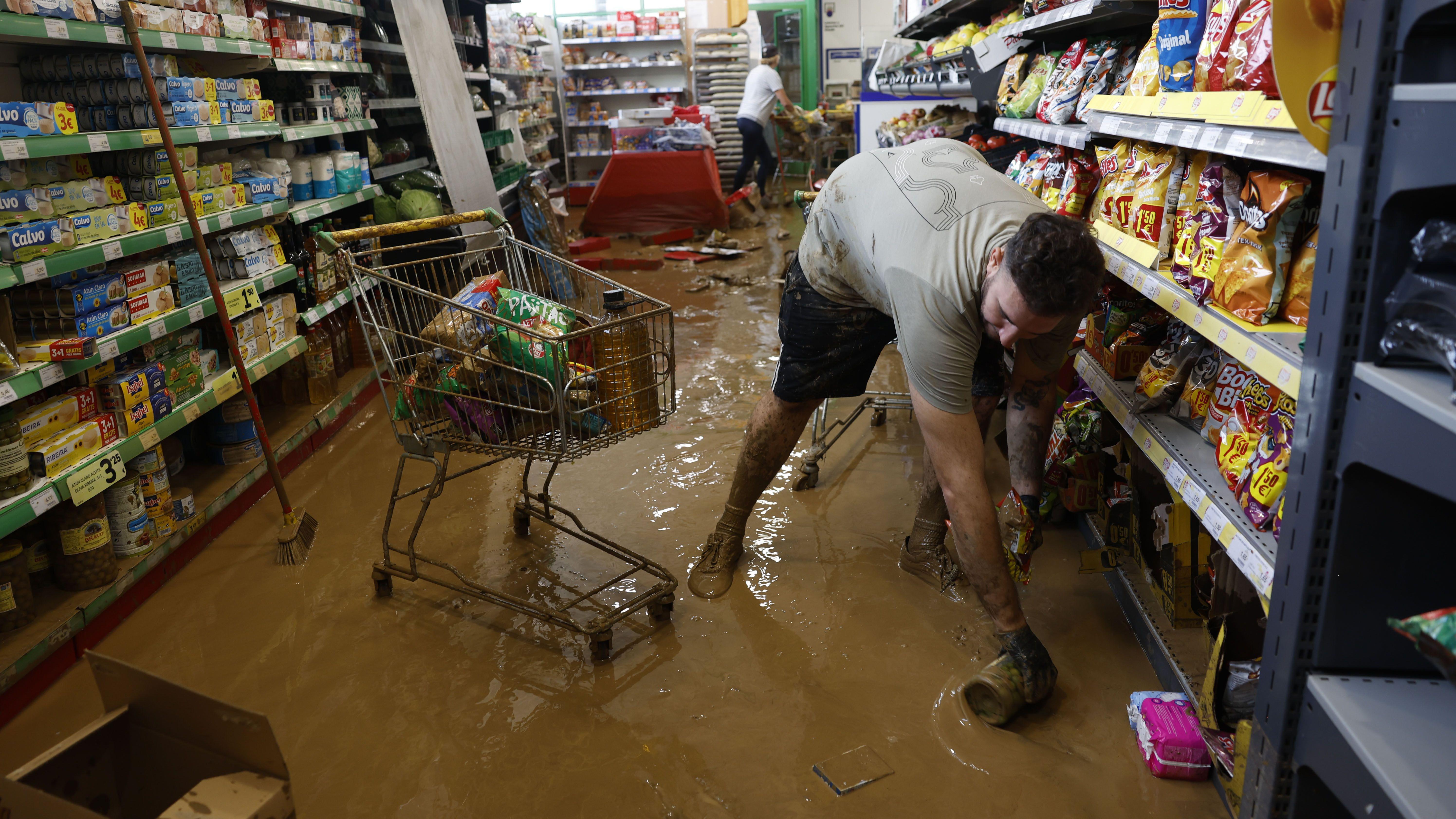 Los trabajadores de una tienda de comestibles retiran barro que entró tras el paso de la tormenta  