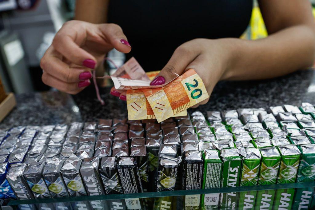 mãos femininas contando dinheiro em balcão de comércio