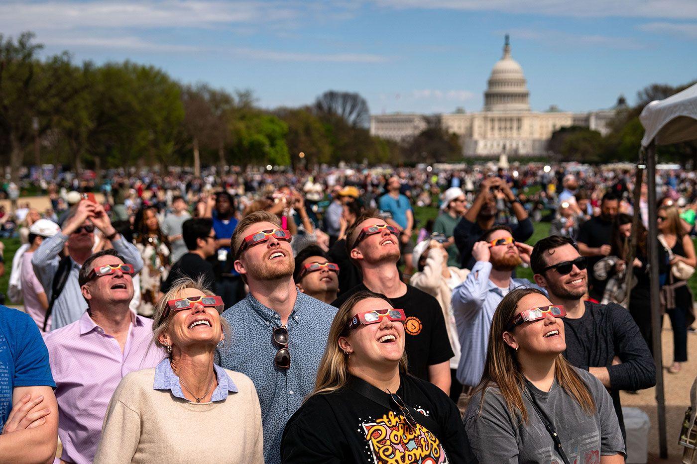 Multidão observando o eclipse com óculos de proteção
