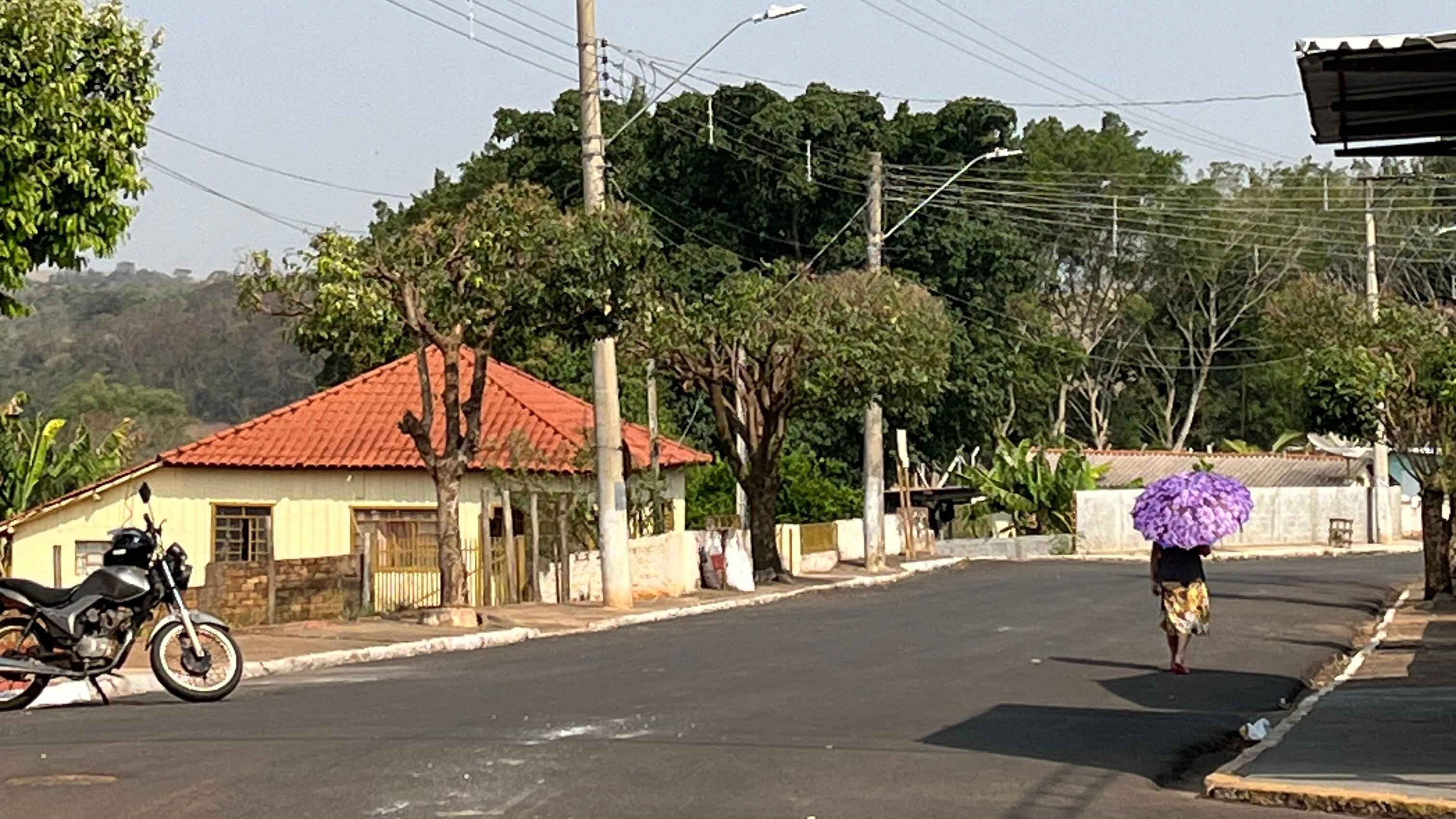 Pessoa caminhando com guarda-sol em rua vazia