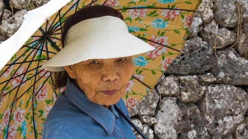 Mulher idosa com sombrinha japonesa em Okinawa
