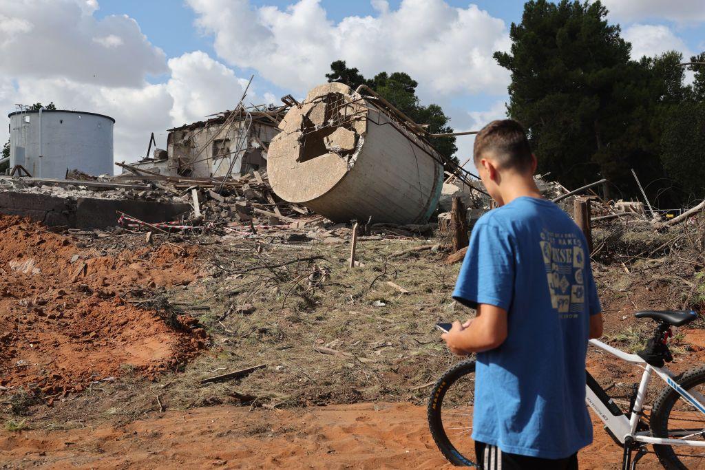 Menino de bicicleta observa os escombros de um edifício destruído