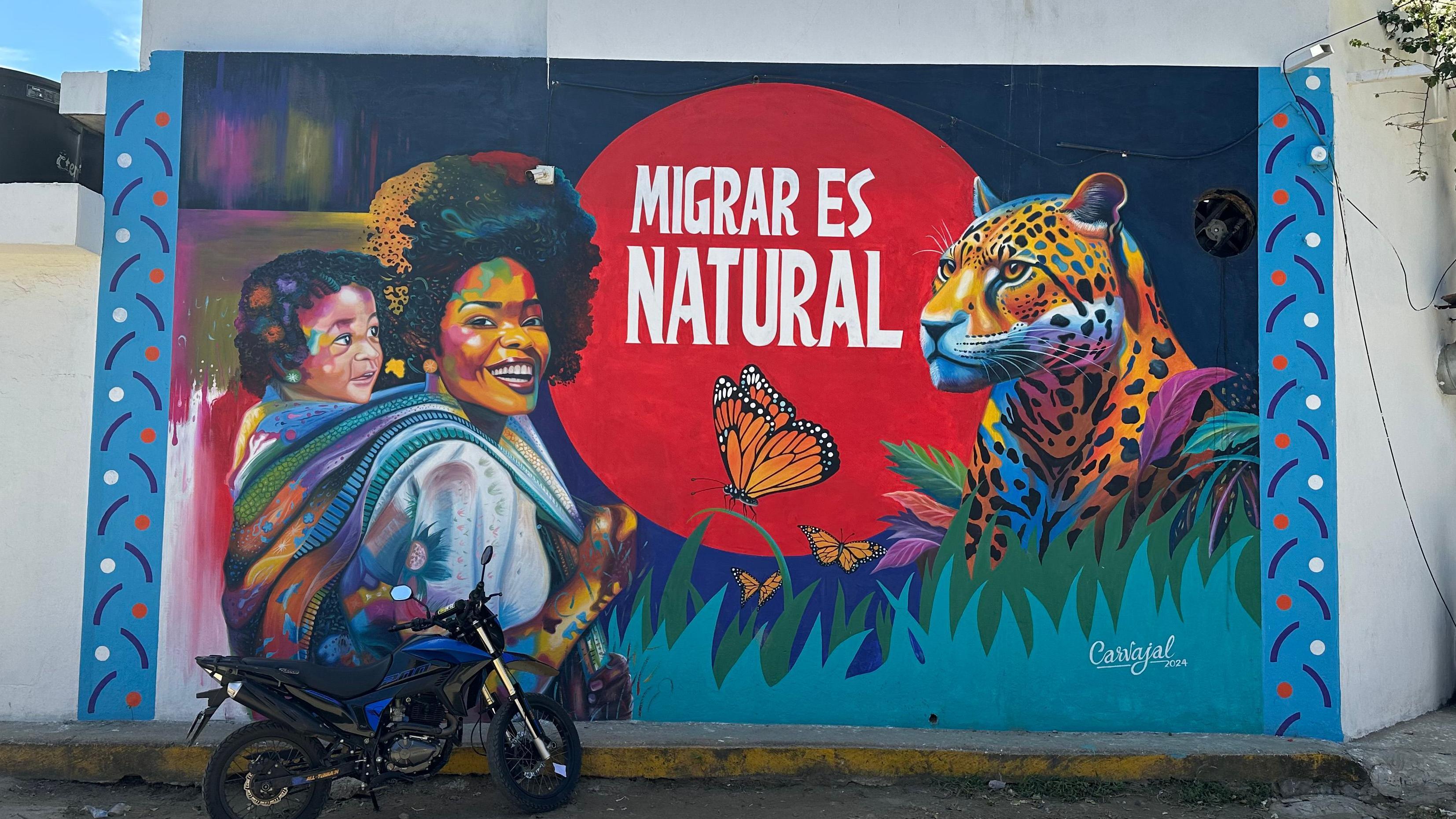 Mural de arte urbano en Necoclí que dice que "migrar es natural".