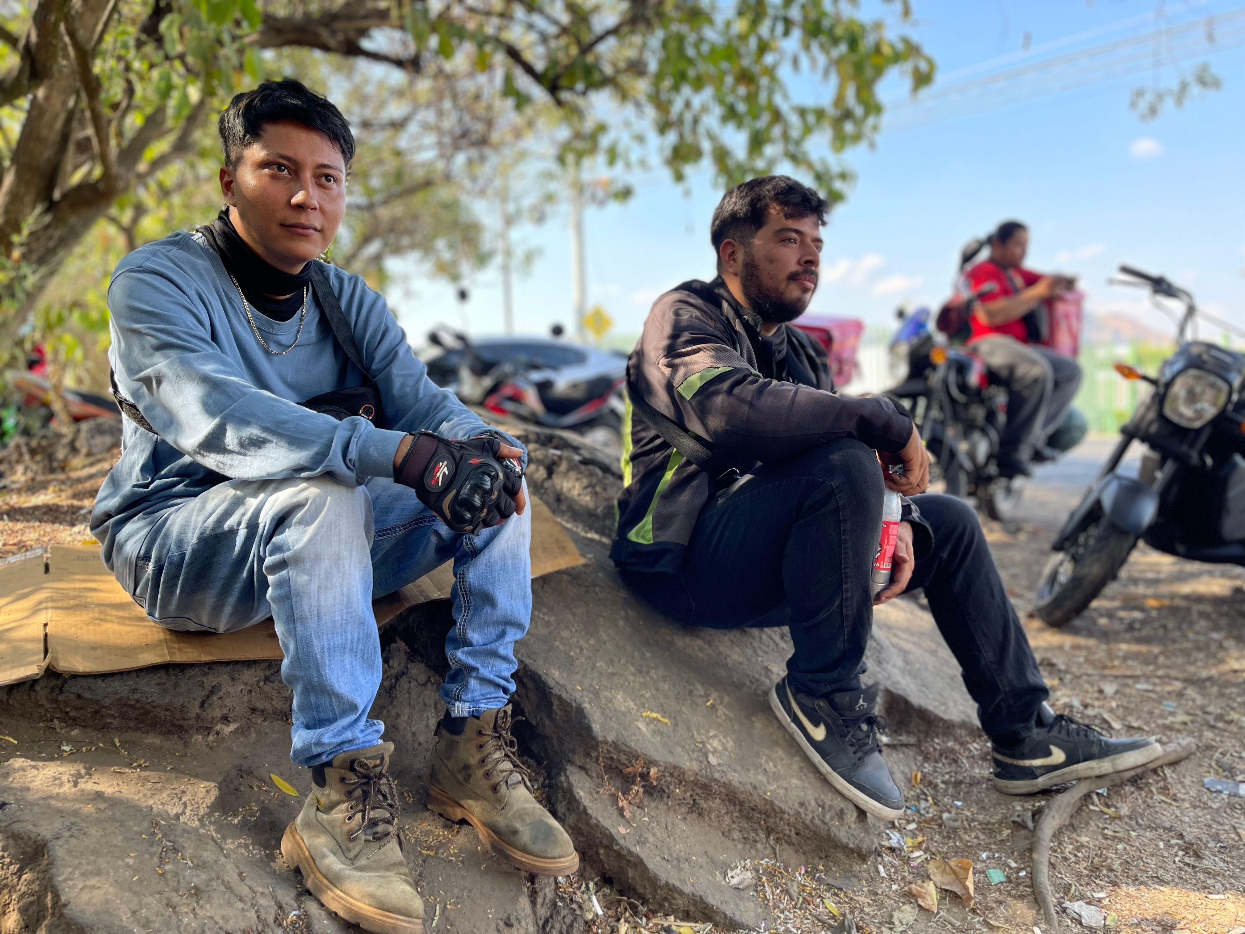 Matías Ruiz y Ezequiel Flores, repartidores autónomos a domicilio que trabajan para Pedidos Ya esperan fuera del centro comercial Metrocentro en Santa Ana, El Salvador, en febrero de 2024.