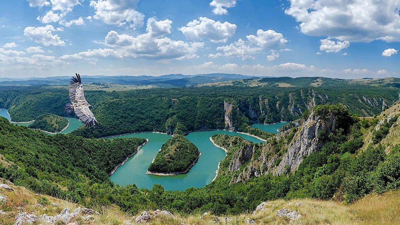 Foto do topo de uma montanha com a paisagem cercada por um rio abaixo