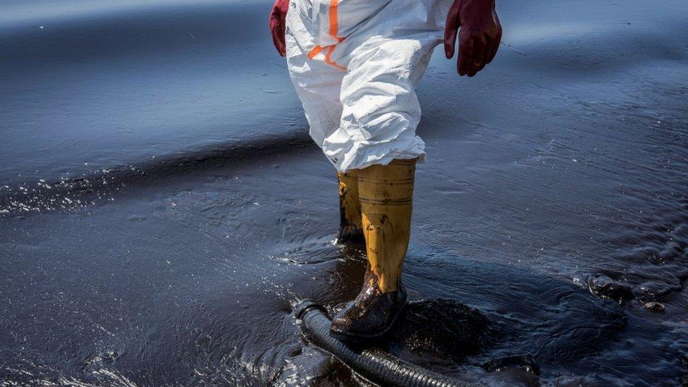 Homem caminhando sobre vazamento de petróleo