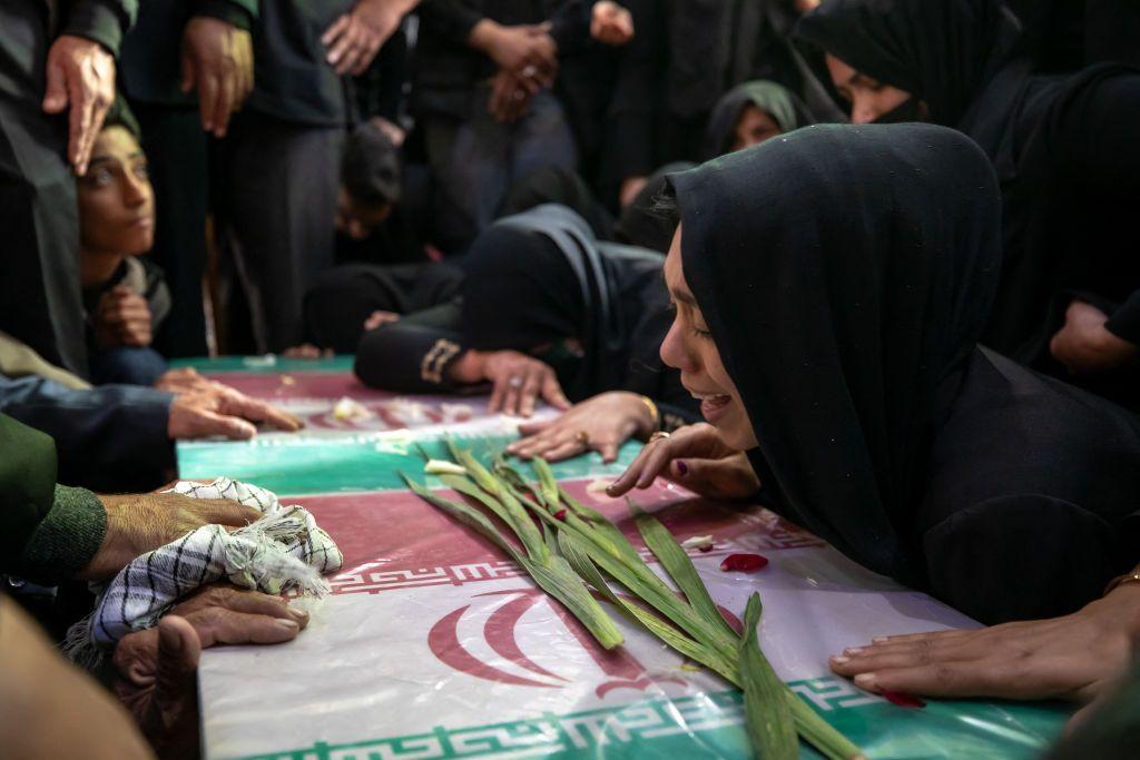 Personas lloran sobre los ataúdes de víctimas del ataque suicida durante el aniversario de la muerte de Qasem Soleimani en Irán.