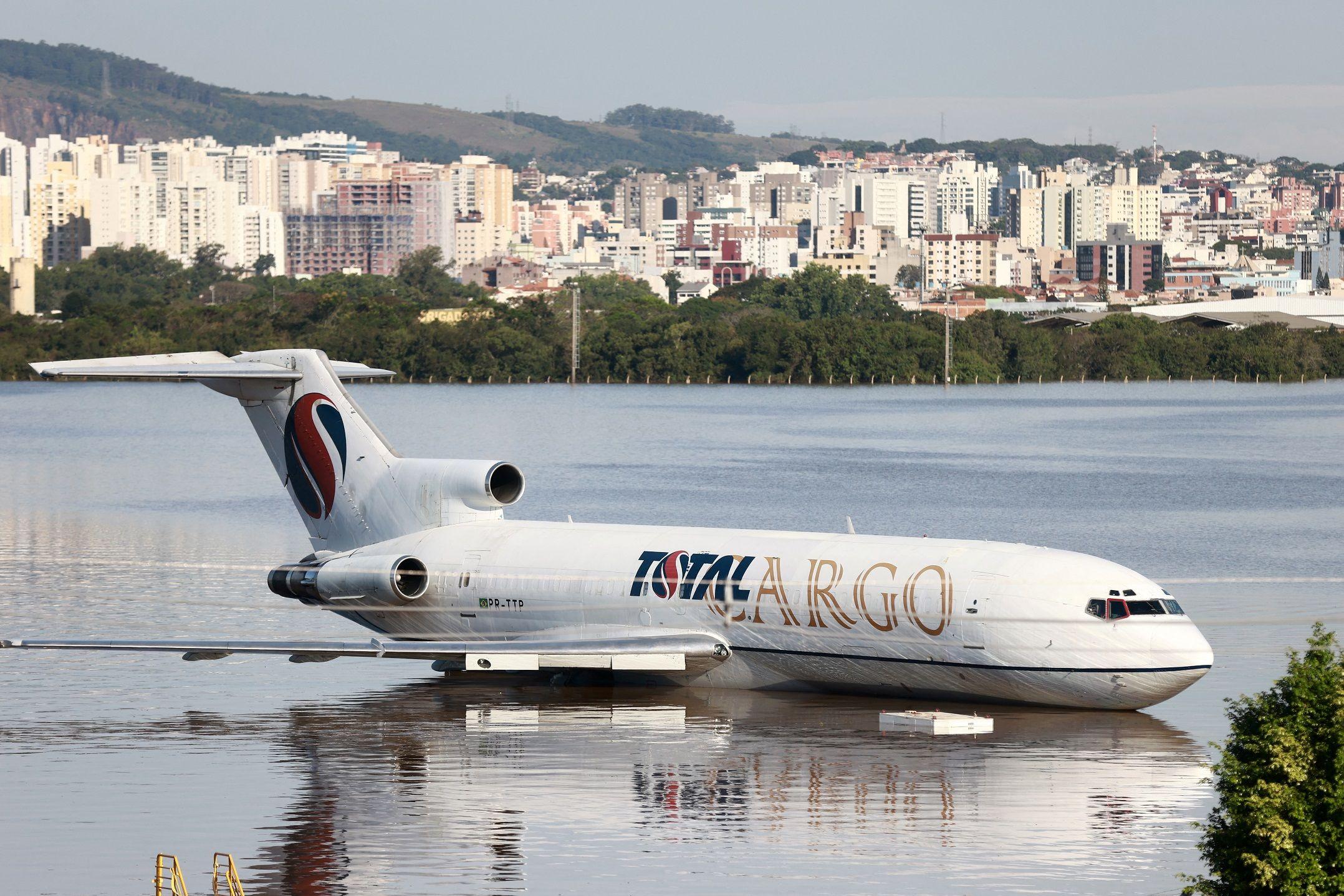 Fotografia mostra pista de avião alagada e avião de carga em meio à água