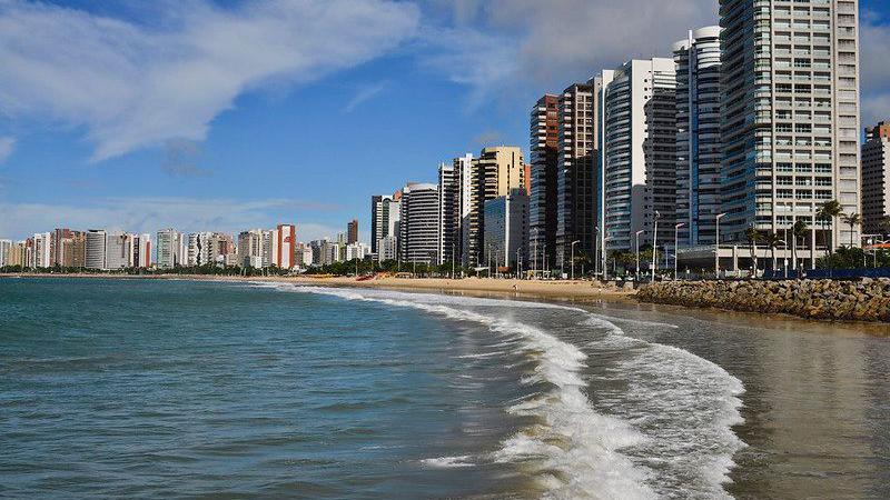 Imagem da orla de Fortaleza, com prédios de um lado e o mar do outro