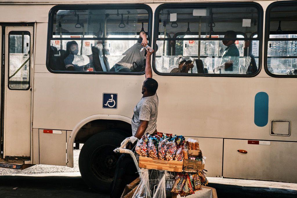 Um vendedor ambulante informal vende uma garrafa de água para um passageiro na Rodoviária do Plano Piloto, principal centro de transporte do Distrito Federal