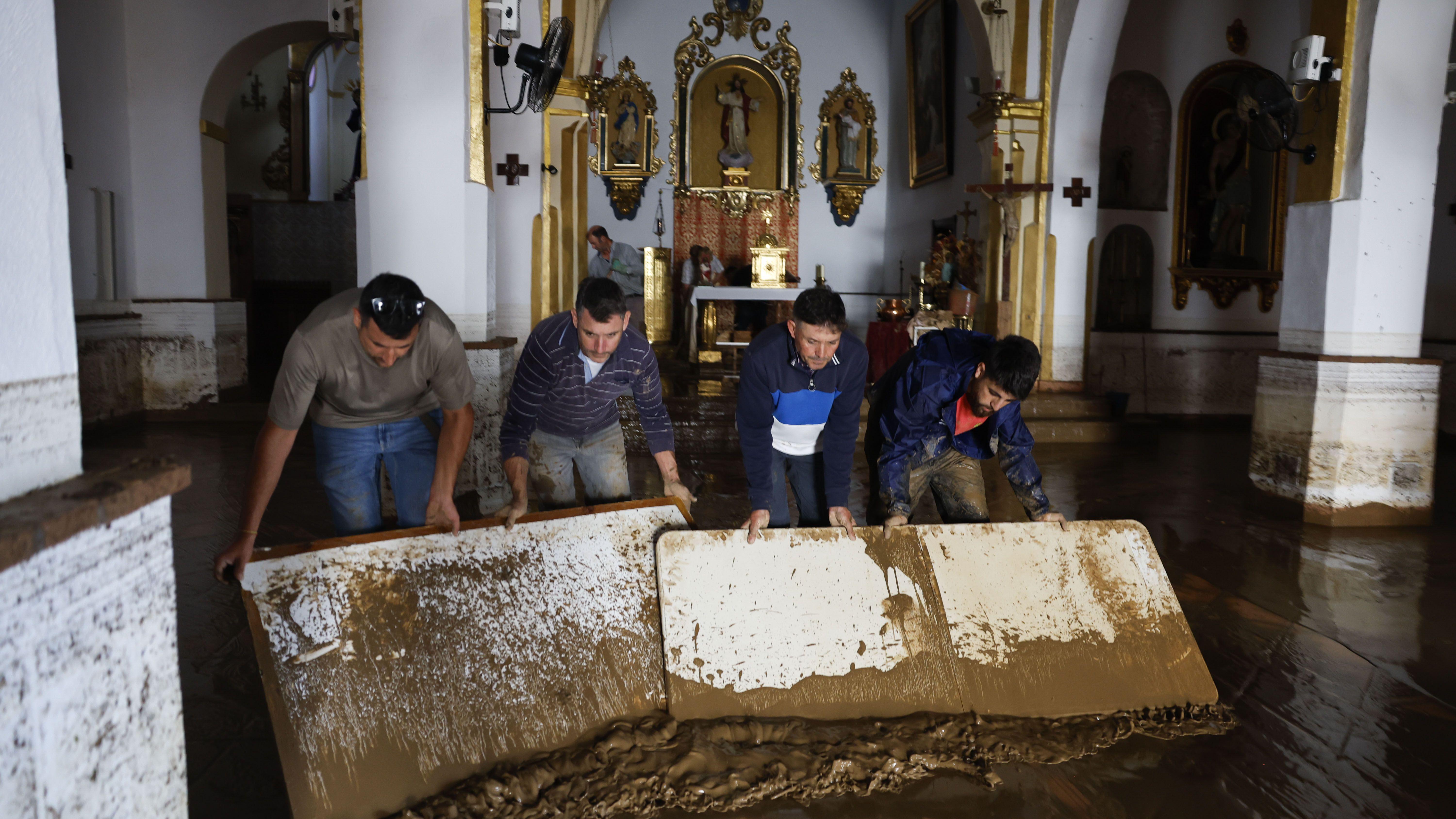 Unos hombre retiran barro de una iglesia. 