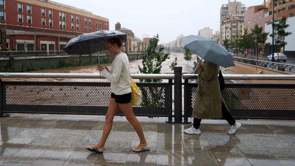 Dos mujeres cruzan un puente sobre el río Guadalmedina cerca del centro histórico de la ciudad de Málaga