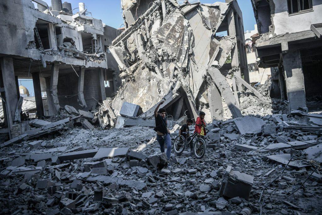 Dos personas paradas sobre los escombros de un edificio bombardeado.
