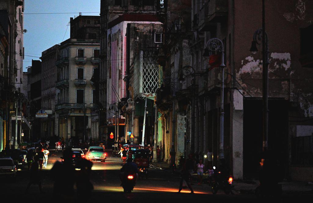 Rua escura de Havana, com iluminação vinda de carros