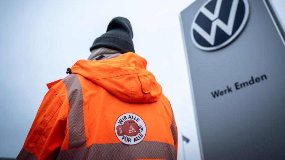 Una mujer con una chaqueta naranja se suma a la huelga en una de las fábricas de VW.