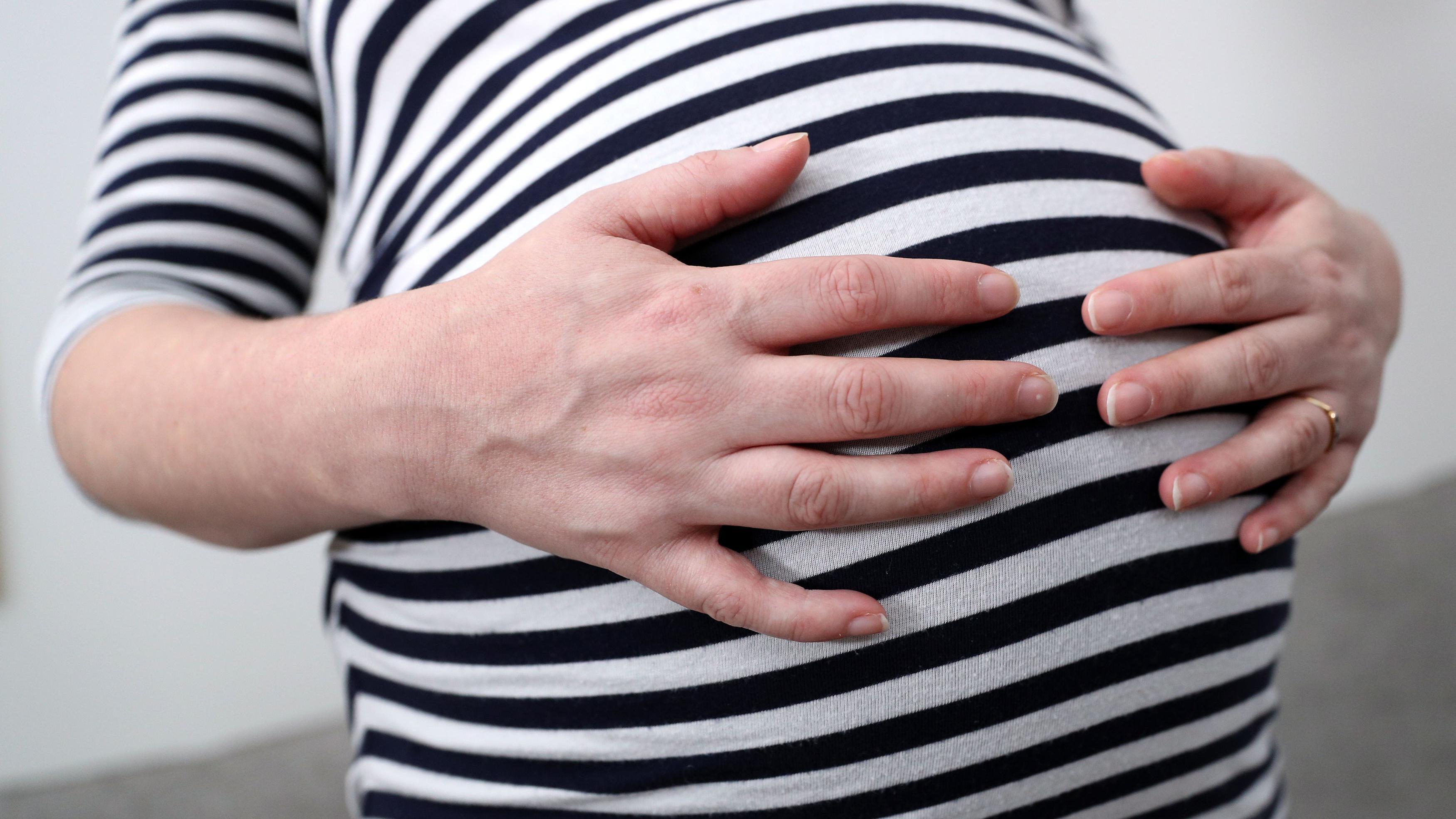 Mulher grávida com as mãos na barriga
