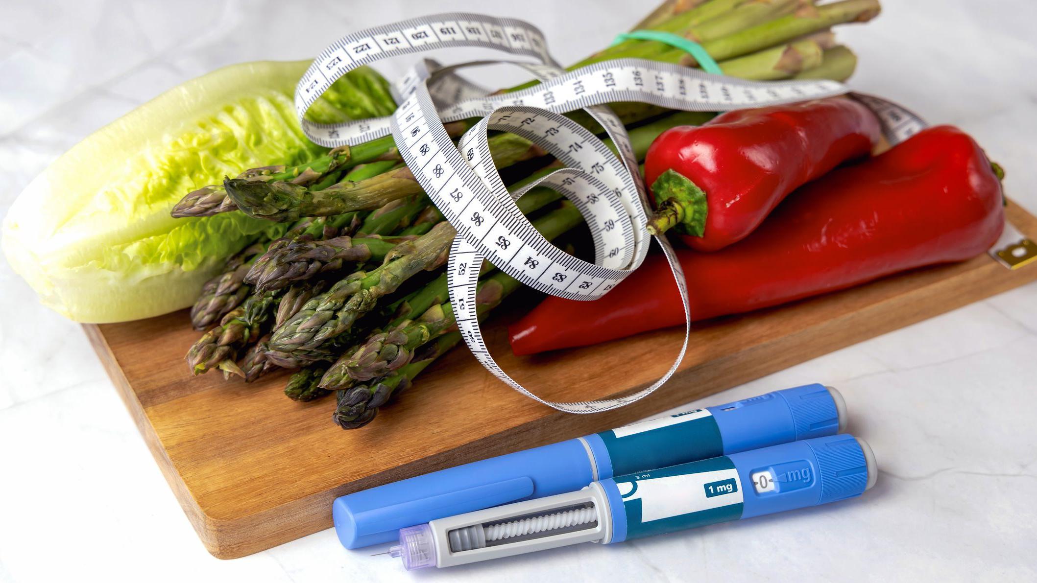 A board with vegetables, a measuring tape and injections of weight loss medications