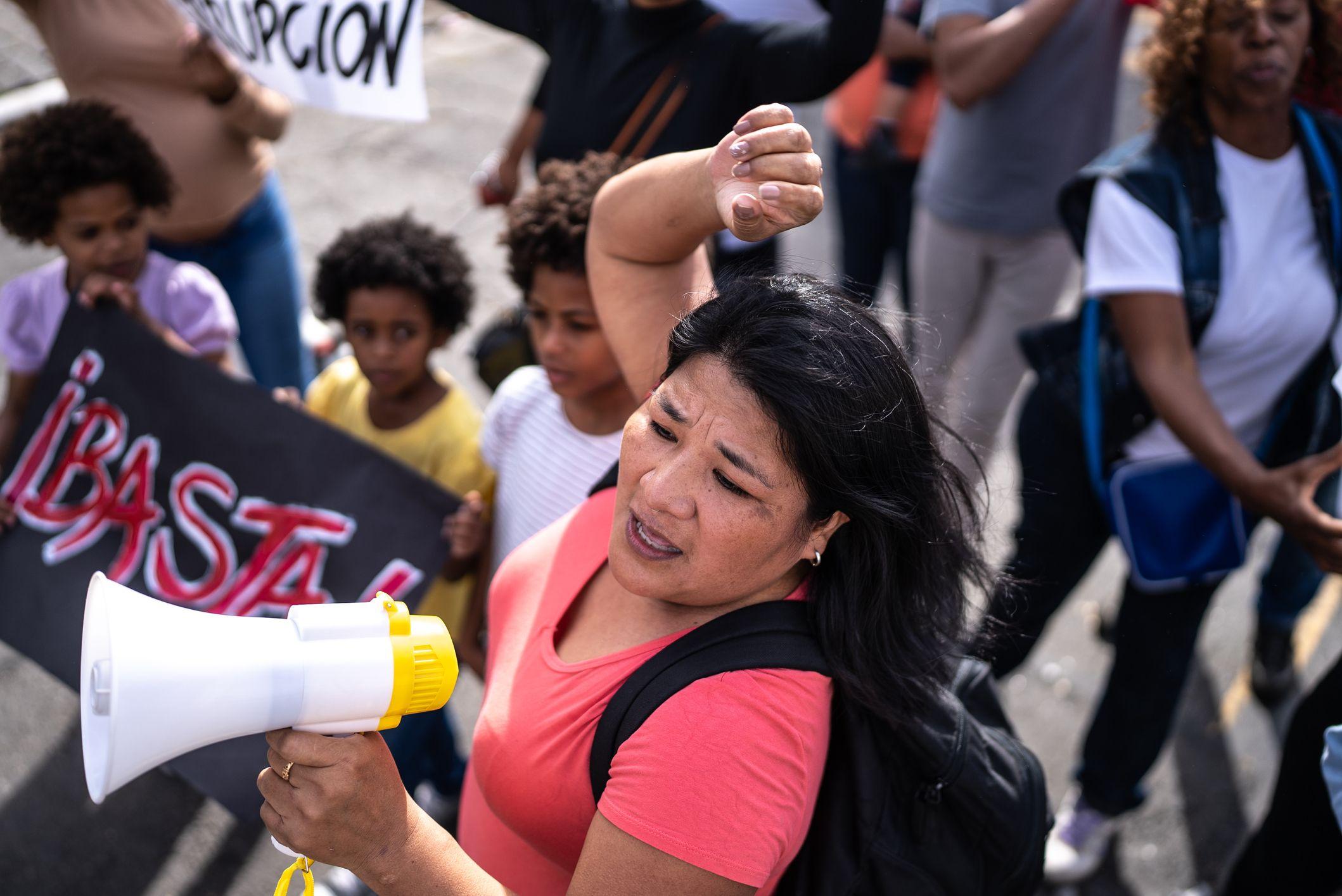 Una mujer protesta con un megáfono en la mano.