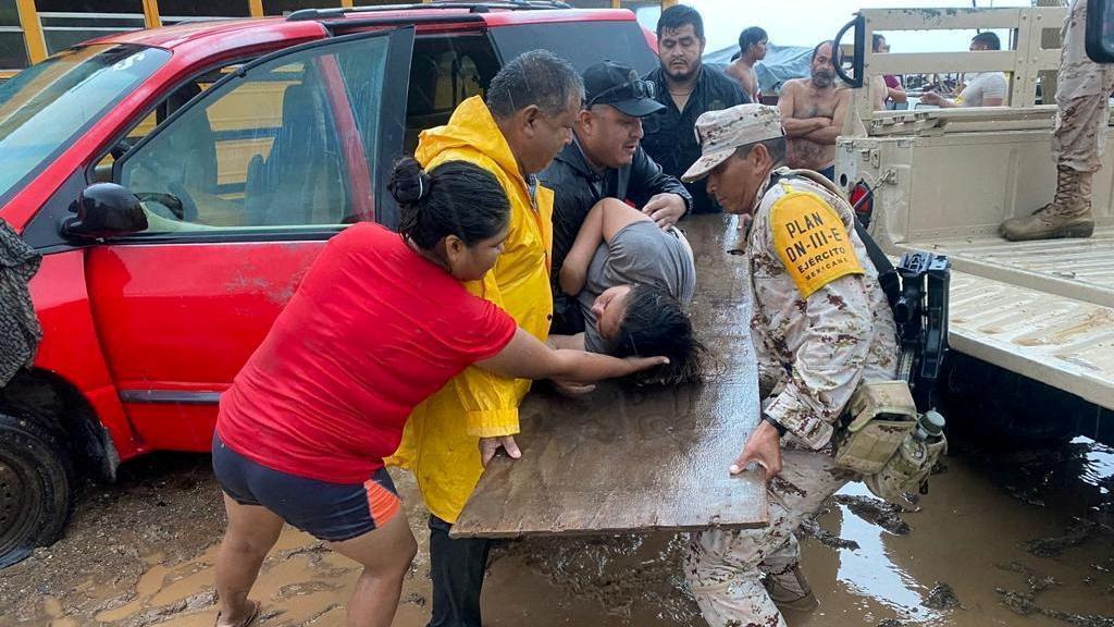Agentes del Ejército mexicano asisten a una mujer en la península de Baja California por el paso de la tormenta tropical Hilary.