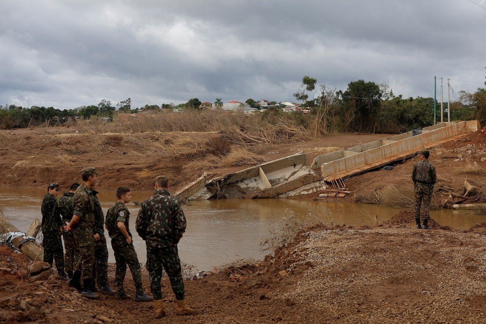 Soldados observam ponte caída em rio