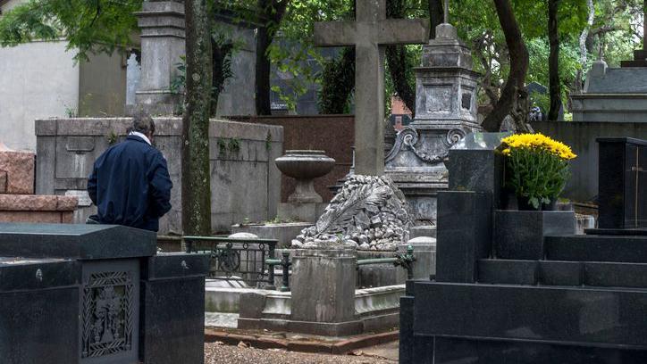 Homem visitando túmulo em cemitério