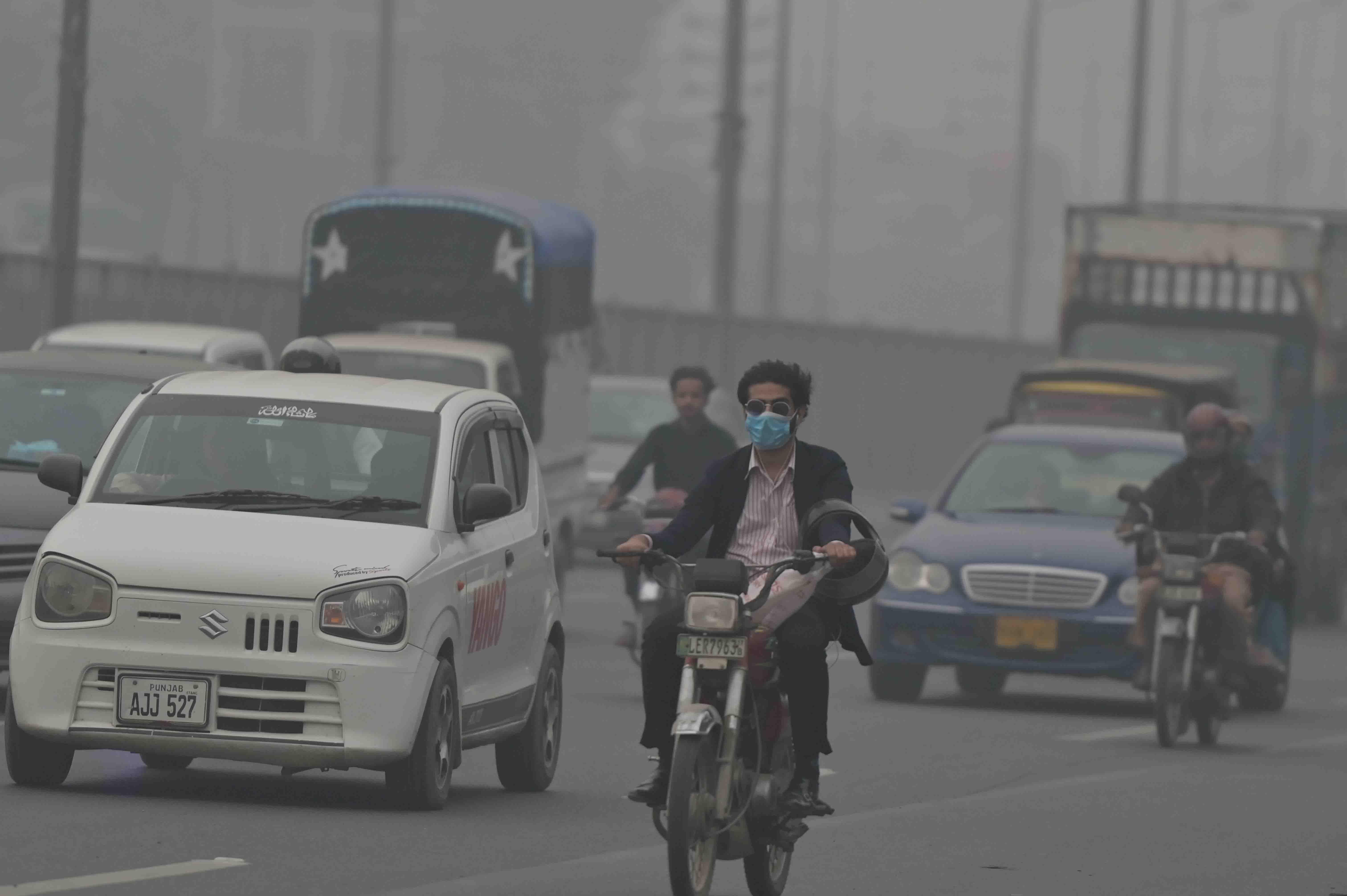 Muškarac sa maskom na licu vozi motor ulicama Lahora u Pakistanu