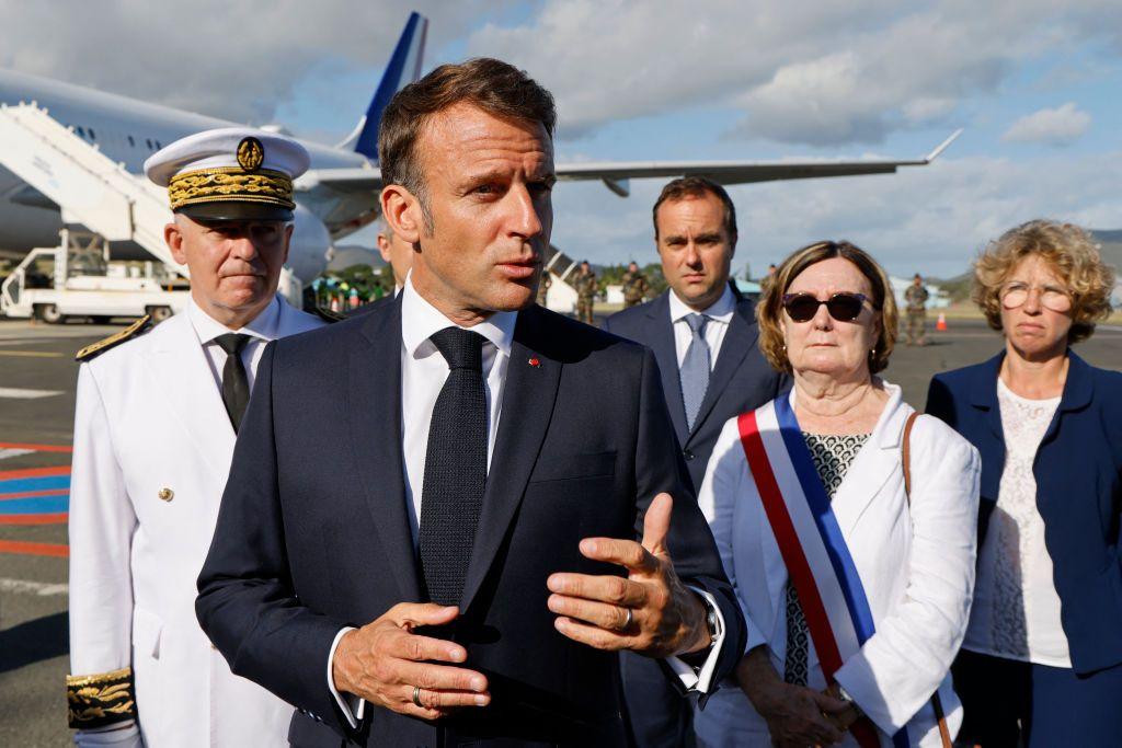 El presidente Macron habla en el aeropuerto de Numea, con autoridades locales detrás. 