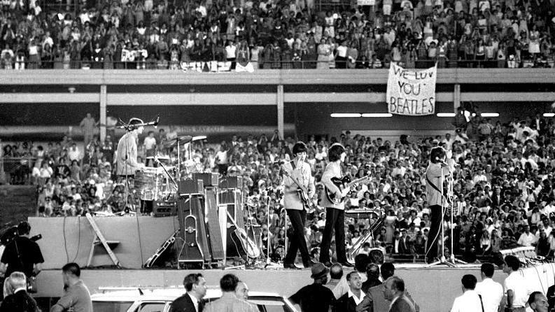 Vista lateral dos Beatles no palco durante um show no Shea Stadium, em Nova York, em 1965