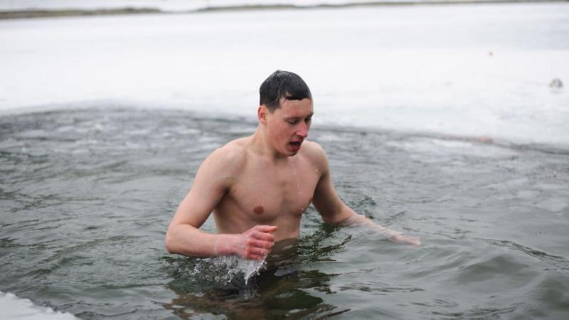 O homem mergulha em águas frias de um lago congelado