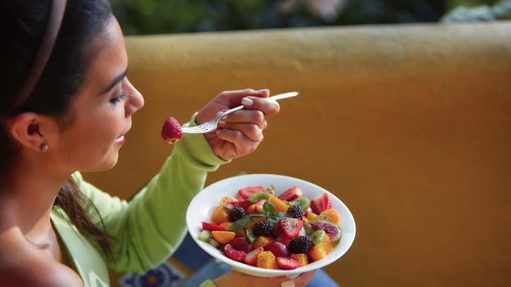 Mulher comendo salada de frutas