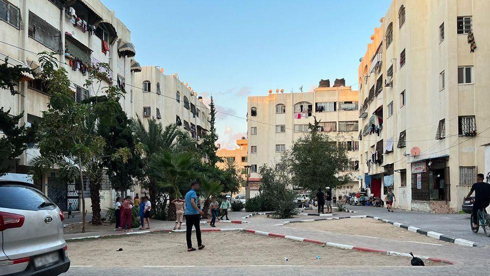 Una toma diurna de Al-Zahra antes del bombardeo, con una gran plaza rodeada de bloques de apartamentos.