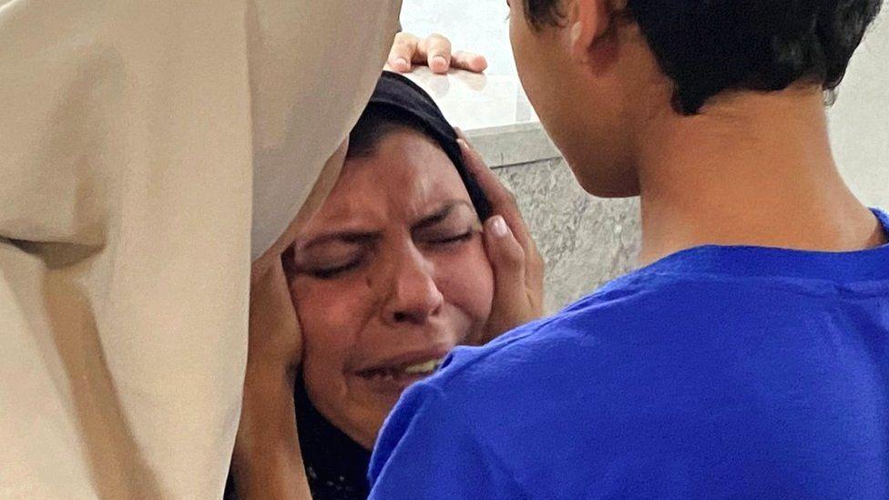 Oğlu İsrail hava saldırısında ölen bir anne, diğer oğlu tarafından sakinleştiriliyor.