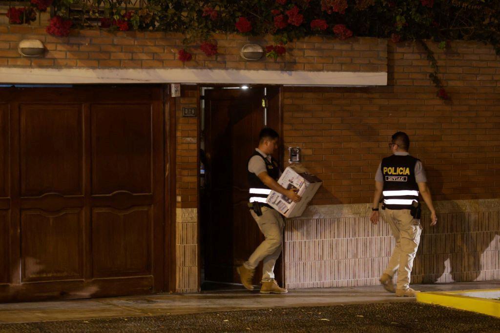 Un policía sale con una caja en mano de la residencia de Dina Boluarte
