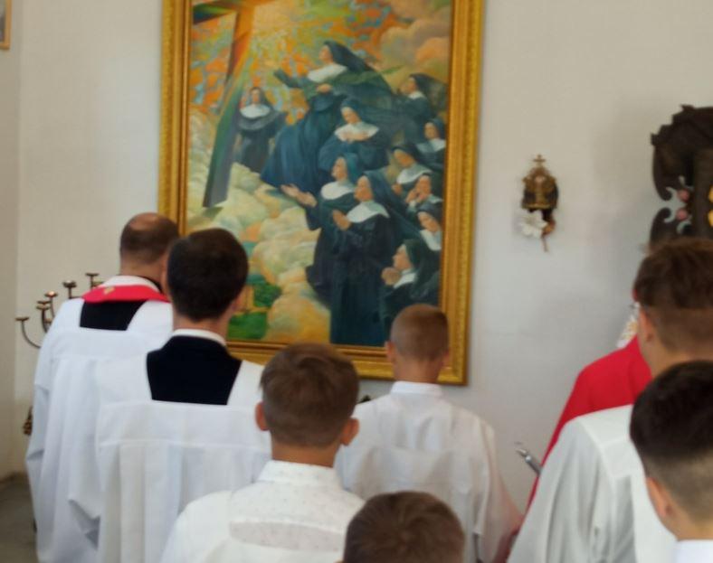 Jovem padre fazendo uma oração diante da pintura dos Mártires de Nowogrodek
