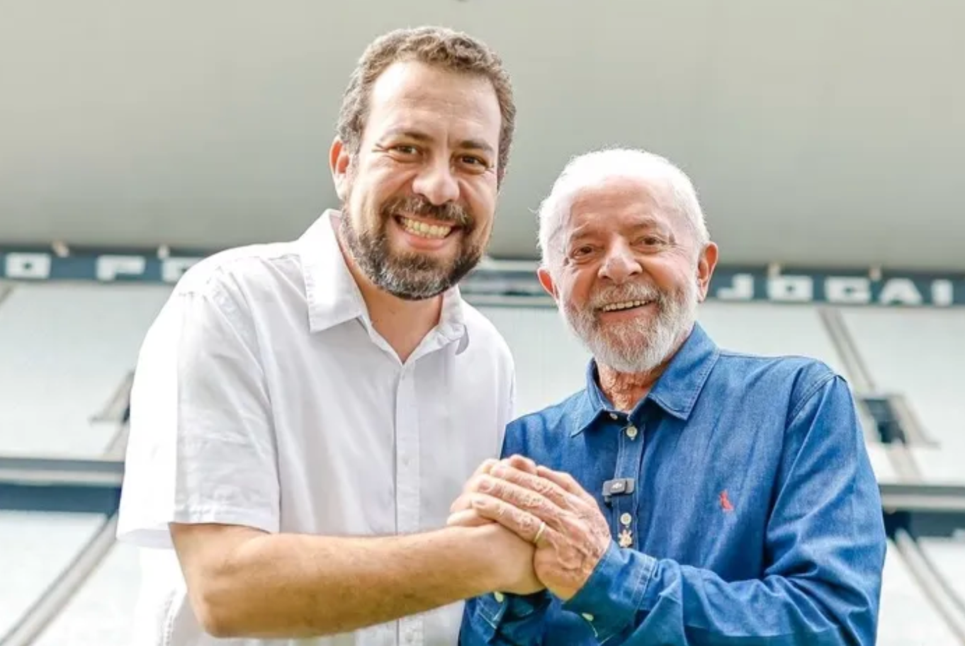 Lula usando camisa azul e Guilherme Boulo usando camisa branca dentro de um estádio